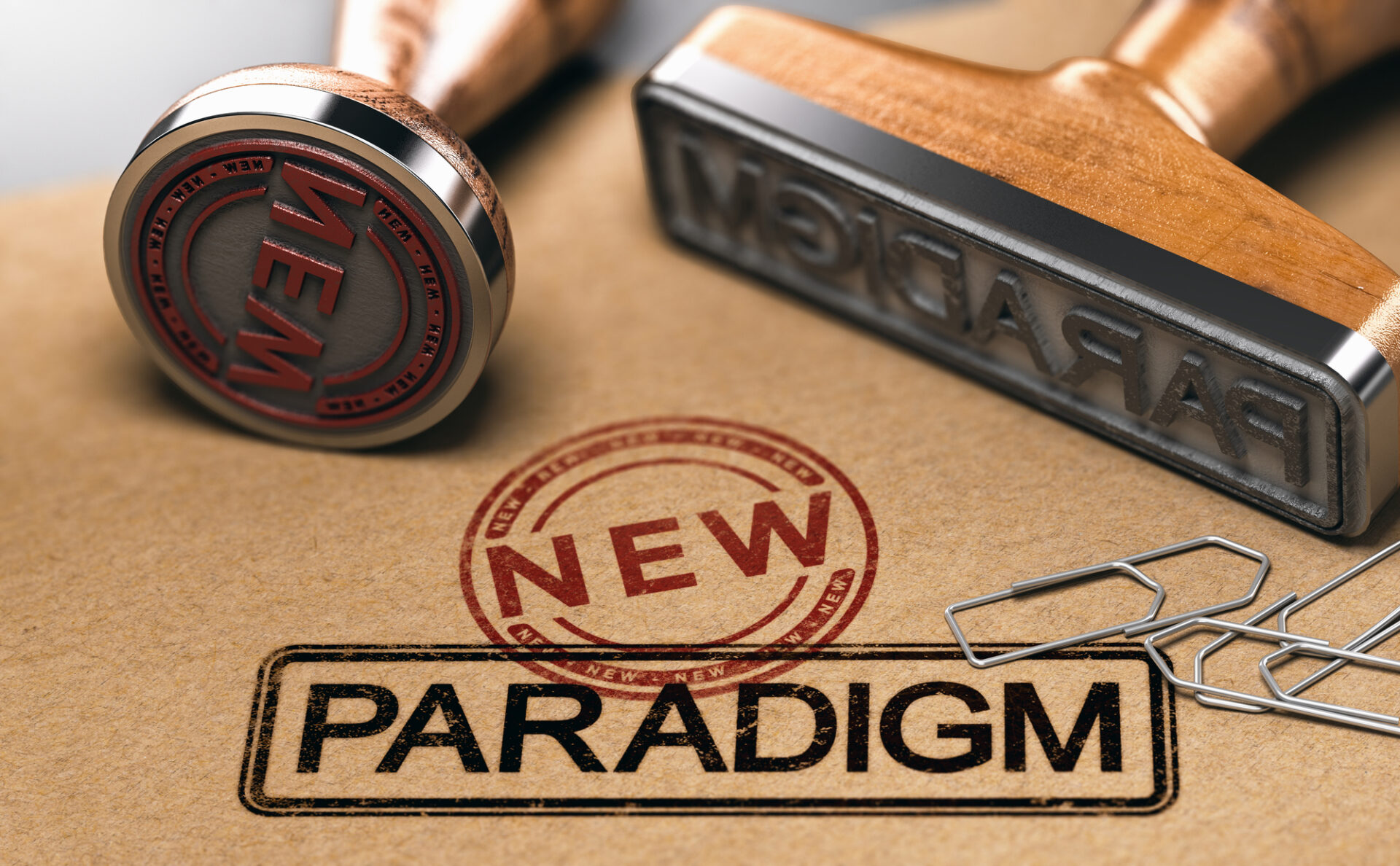 Rubber stamps with the words new and paradigm over brown paper background. 3D illustration