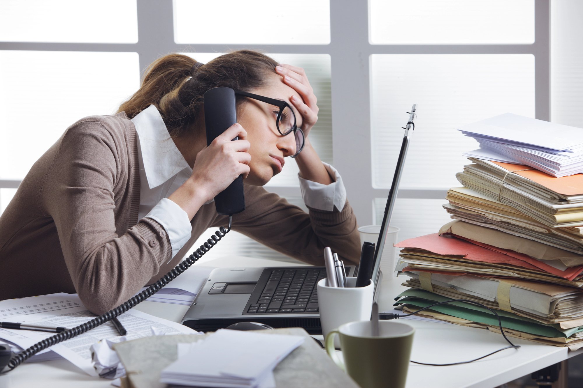 Women at work on phone stressed surrounded by papers