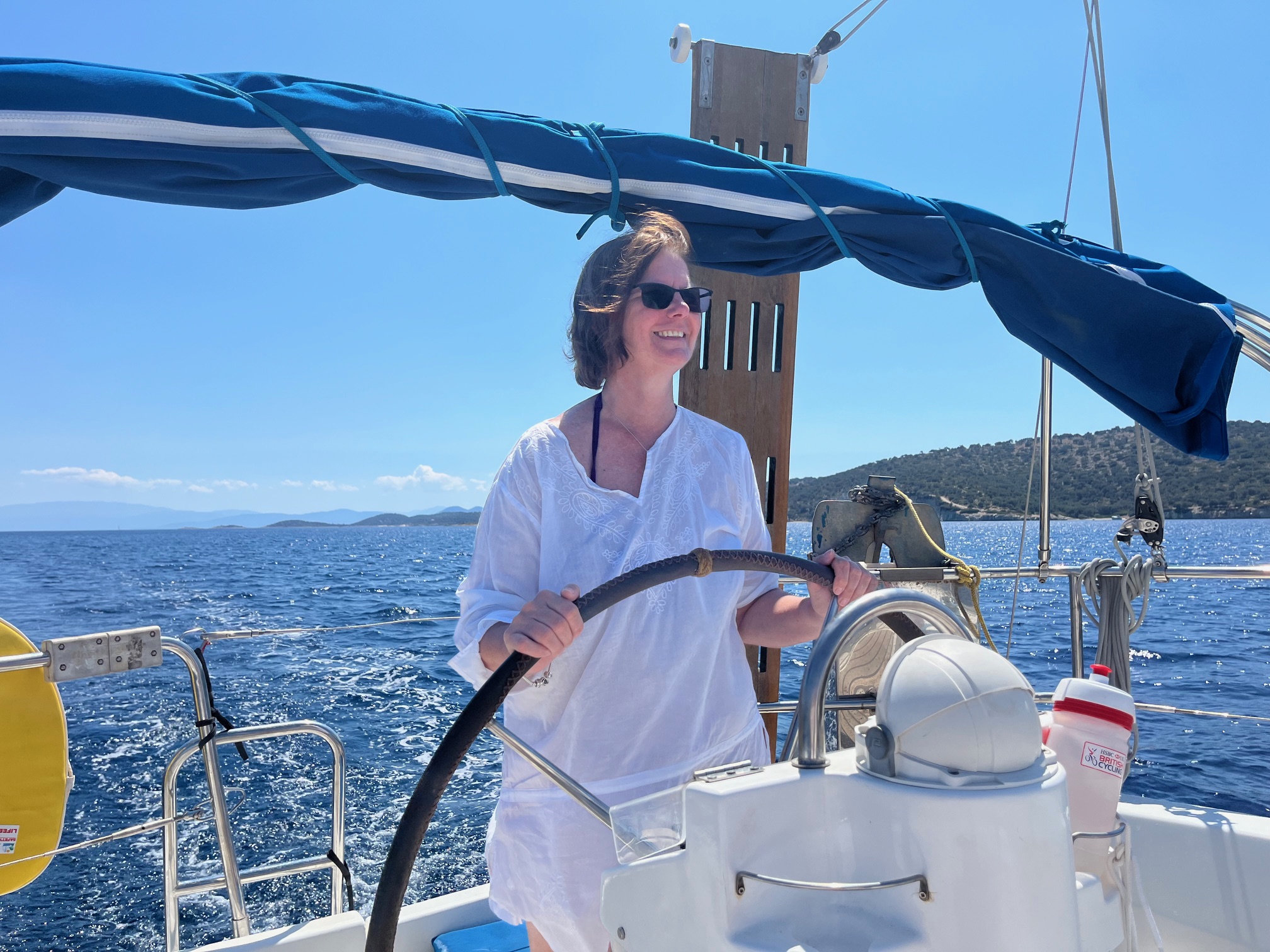 a woman sailing a boat at the helm