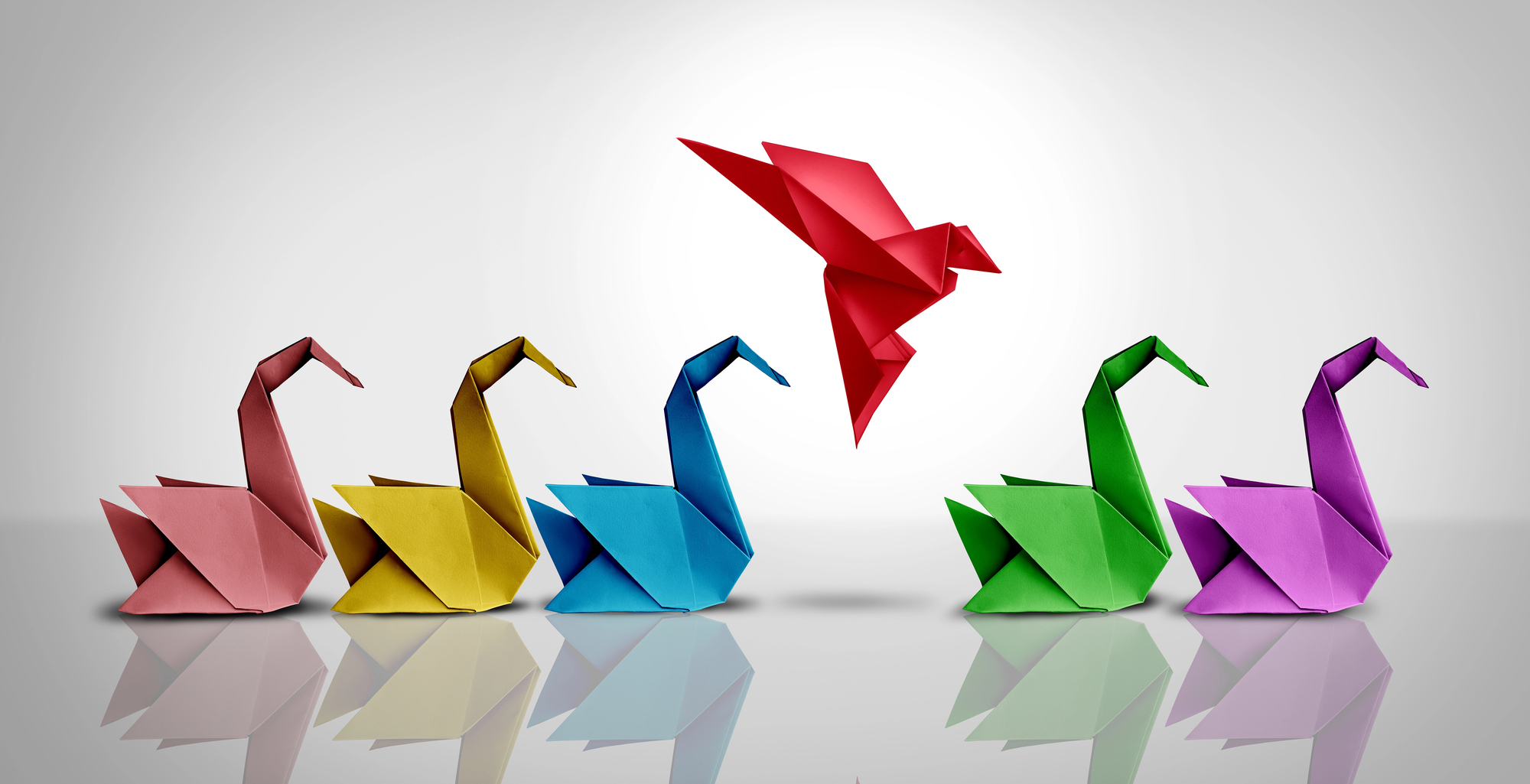 Paper swans in different colours and a red bird flying in